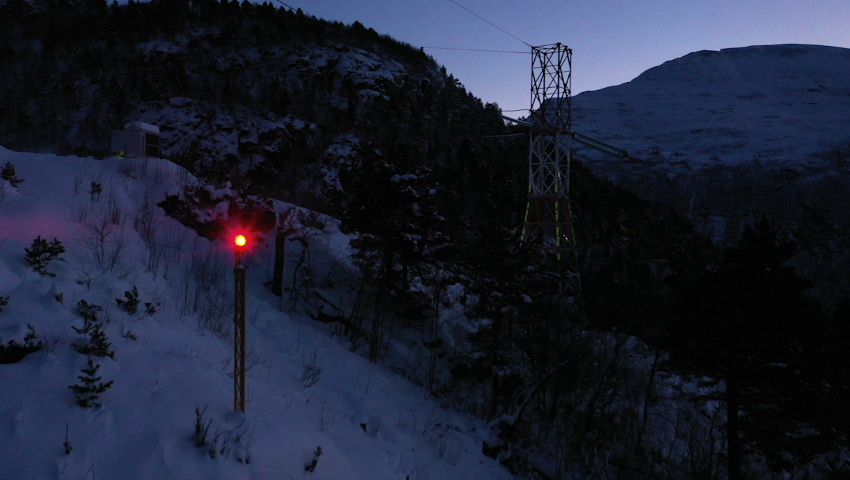 Hinderlysene vil som regel bli satt opp regel satt opp på en stolpe ved siden av høyspentmasten, men noen installeres på toppen av skapet eller i høyspentmasten. Bildet er tatt i 2020 i forbindelse med at Statnett installerte 20 pilotlys for å teste lysene ute i felt.
